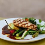 Savor a delicious grilled chicken breast paired with fresh vegetables, elegantly plated.