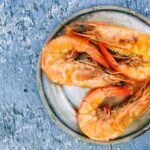 Top view of cooked shrimps on a metal plate on rustic surface. Perfect for seafood lovers.