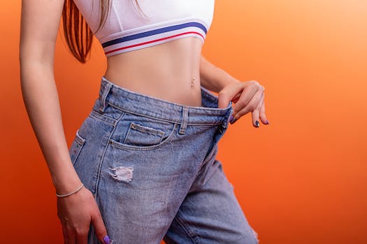 A woman holding loose jeans against her slim waist, symbolizing successful weight loss.