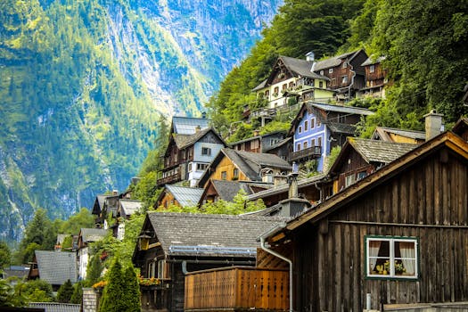 Charming wooden houses on a lush mountainside in Hallstatt, Austria under bright daylight.