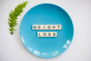 A blue plate with 'weight loss' tiles and a fern leaf on white background.