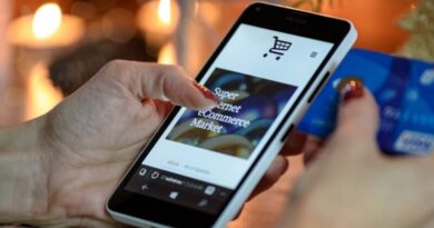 Woman using smartphone for online shopping with credit card in hand, festive background lighting.