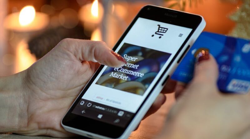 Woman using smartphone for online shopping with credit card in hand, festive background lighting.