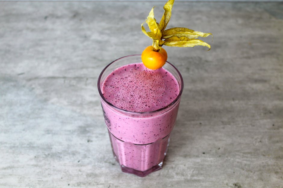 Delicious homemade purple smoothie in a glass topped with a vibrant physalis fruit.