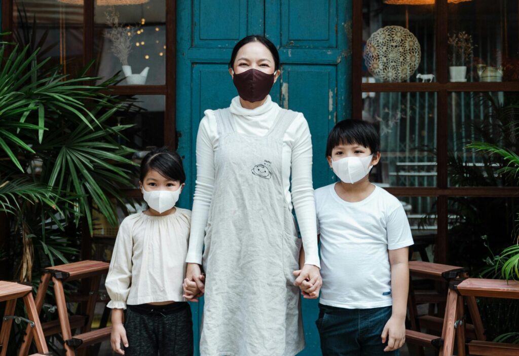 A family wearing face masks standing outside a cafe during daytime.