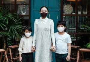 A family wearing face masks standing outside a cafe during daytime.